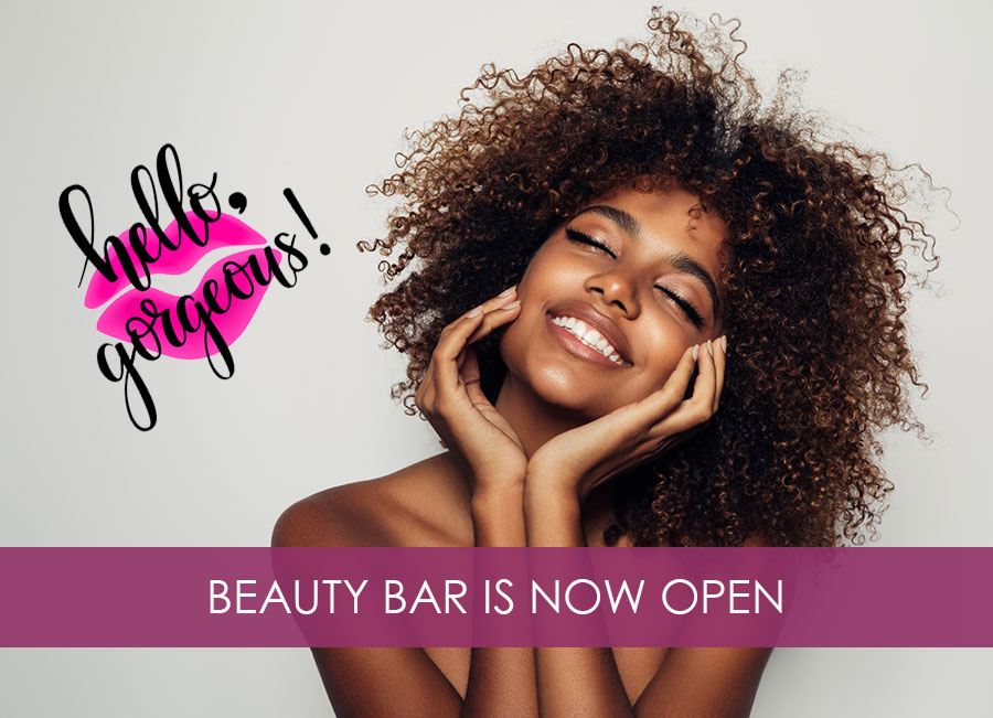 Woman smiling next the beauty bar banner